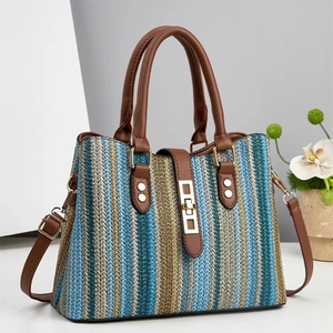 Striped straw tote bag with brown leather handles and golden lock on neutral background