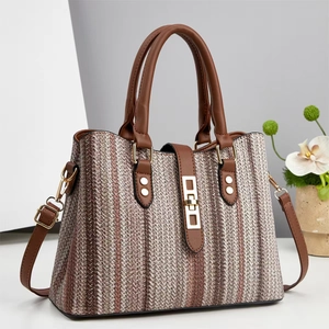Detail of striped woven tote bag with brown leather handles and gold metal hardware