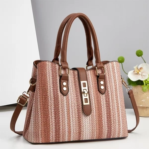 Close-up of striped woven tote bag with brown faux leather handles and gold metal buckle