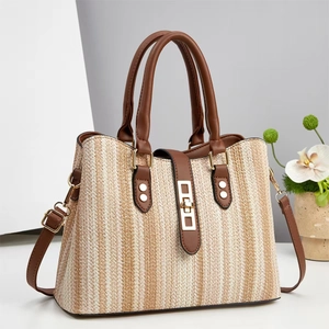 Detail of woven striped tote featuring brown leather handles and matte gold hardware