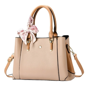 Women's beige pebbled crossbody bag with tan handles and decorative floral scarf
