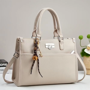 Detail of off-white lychee grain leather handbag with silver lock and decorative charm