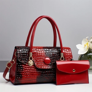 Detail of red crocodile texture handbag set with polished gold hardware and matching pouch