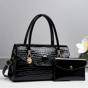 Detail of black crocodile texture patent leather handbag set with gold lion charm