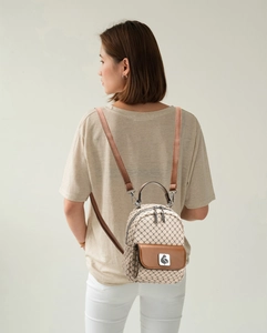 Detail of checkered mini backpack with brown leather pocket and bird logo on model