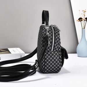 Detail of a black and white geometric grid backpack with double zipper and silver hardware