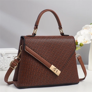 Close-up of dark brown textured leather handbag with gold twist lock and elegant floral backdrop