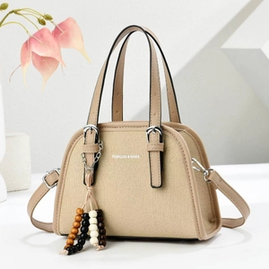 Close-up of beige canvas shoulder bag with fashion text and ethnic beaded charm