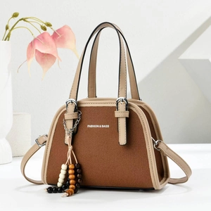 Retro brown canvas tote bag with beige leather trim and beaded tassel on white stand