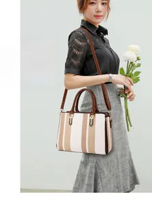 Close-up of contrast striped tote bag with leather handles and gold metal hardware