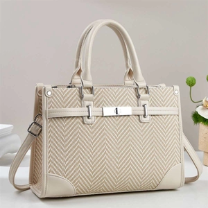 Detail of herringbone fabric tote bag with cream leather trim and gold metal clasp lock