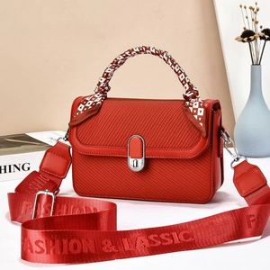 Detail of red square crossbody bag with silk scarf handle and wide branded fabric strap