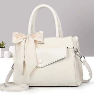 Detail of cream white leather handbag with ribbon bow and metal magnetic snap closure