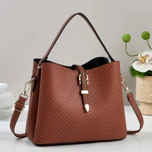 Close-up of brown tote bag showing herringbone weave texture and gold buckle detail