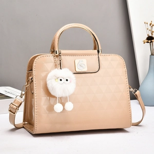 Detail of beige patent leather bag with embossed triangles and cute furry pompom charm