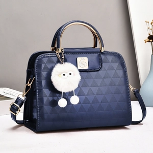 Navy blue embossed leather handbag with golden metal handles and a plush doll pendant