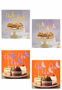 Makroaufnahme von glitzernden Schmetterlings-Kuchendekos und One-Schriftzug für Babys