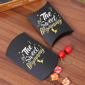 Two black graduation candy boxes with gold text on a warm wooden background