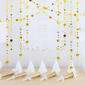 Detail of gold glitter star garlands, party hats, and blowouts for festive birthday decor