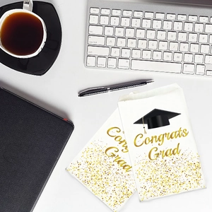 Two white 'Congrats Grad' paper gift bags with gold accents on a modern desk setting