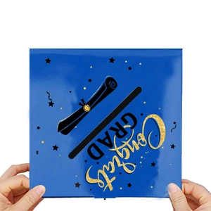 Scatola regalo blu per laurea con scritte Congrats Grad e stelle tenuta su fondo bianco
