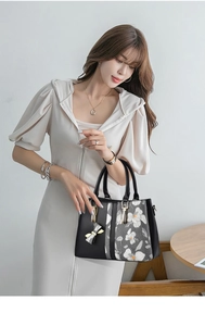 Detail of floral printed handbag with butterfly pendant and gold hardware finish