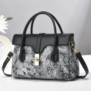 Elegant white jacquard handbag with black leather accents and golden twist lock
