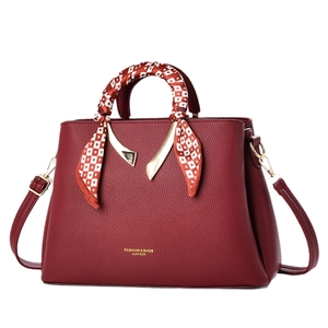 Burgundy textured leather tote with silk scarf handle and golden hardware crossbody strap