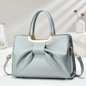 Elegant light blue leather handbag with bow detail and metallic handle in a modern setting