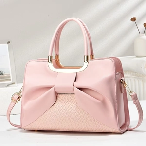 Elegant pink handbag with bow design and gold U-handles on a minimalist white backdrop