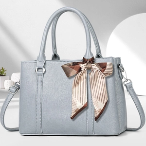 Detailansicht der hellblauen Lederhandtasche mit Litschi-Muster und gestreiftem Seidenschal