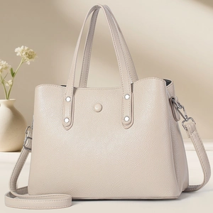 Detail view of cream leather tote bag featuring lychee texture and silver metal rivets