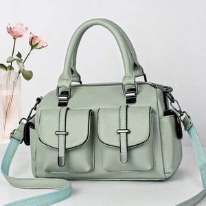 Detail of mint green lychee leather bag with dual front pockets and woven shoulder strap