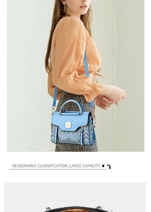 Detail of light blue embroidered handbag showing golden logo and metallic handle hardware