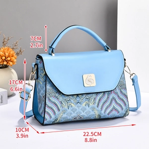 Close-up of light blue crossbody bag featuring a golden bird lock and oriental wave print