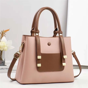 Close-up of litchi texture on pink handbag with brown handle and golden hardware details