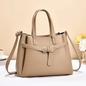 Detail of khaki lychee grain leather tote with silver buckle strap and shoulder strap