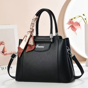 Detail of black lychee grain leather tote bag with silver logo and decorative silk scarf