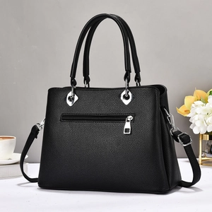Close-up of black litchi texture handbag with silver hardware and back zipper pocket