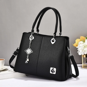 Large black lychee textured tote bag with top handles, crossbody strap and pearl charm