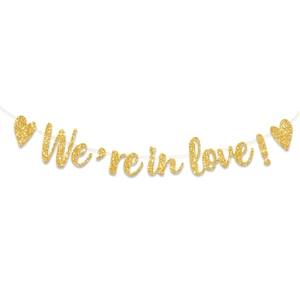 Detail of glittery gold 'We're in love!' banner with heart shapes for wedding decor