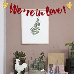 Pancarta roja de purpurina 'We're in love!' con corazones dorados para fiesta de amor
