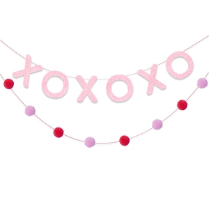 Dettaglio di lettere XOXO rosa glitterate e ghirlanda di pompon rossi decorativi