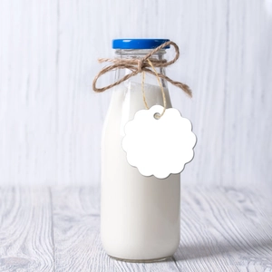 Glass milk bottle with blue cap, twine wrap and blank white scalloped paper tag