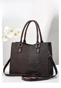 Detail of dark brown faux crocodile leather bag with glossy finish and gold hardware