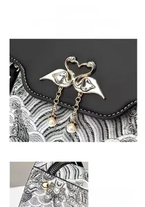 Détail de la broderie et du fermoir cygne doré avec pendentif en perle