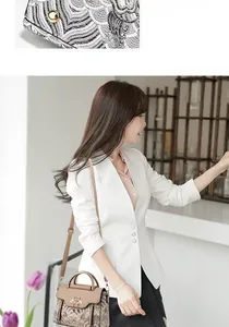 Détails de la broderie latérale et du fermoir papillon doré sur ce sac en cuir beige