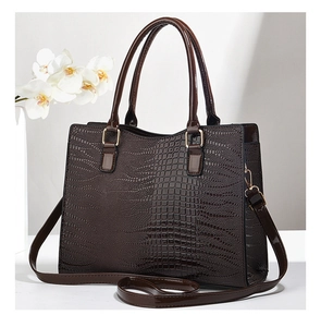 Detail of glossy crocodile embossed texture on a dark brown tote bag with gold hardware