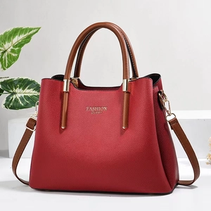 Rote Lederhandtasche mit braunen Griffen und goldener Fashion Queen Aufschrift