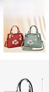 Detail of embroidered floral handbag featuring butterfly patterns and a silk scarf handle